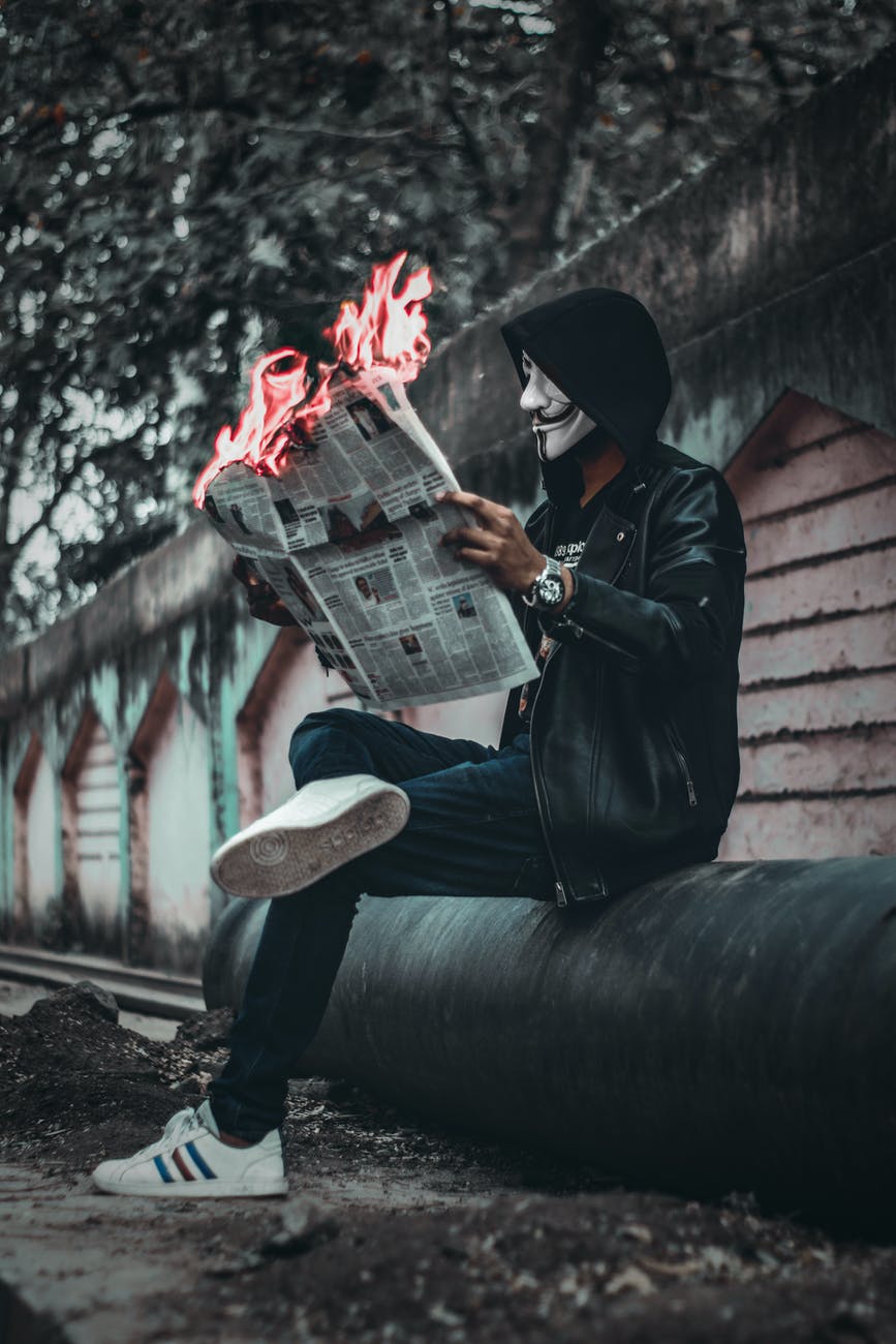 seated man reading newspaper with flames